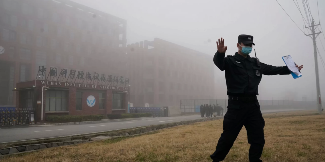 世衛專家小組在湖北實地考察後，一名職員將記者帶離武漢病毒研究所現場。／美聯社